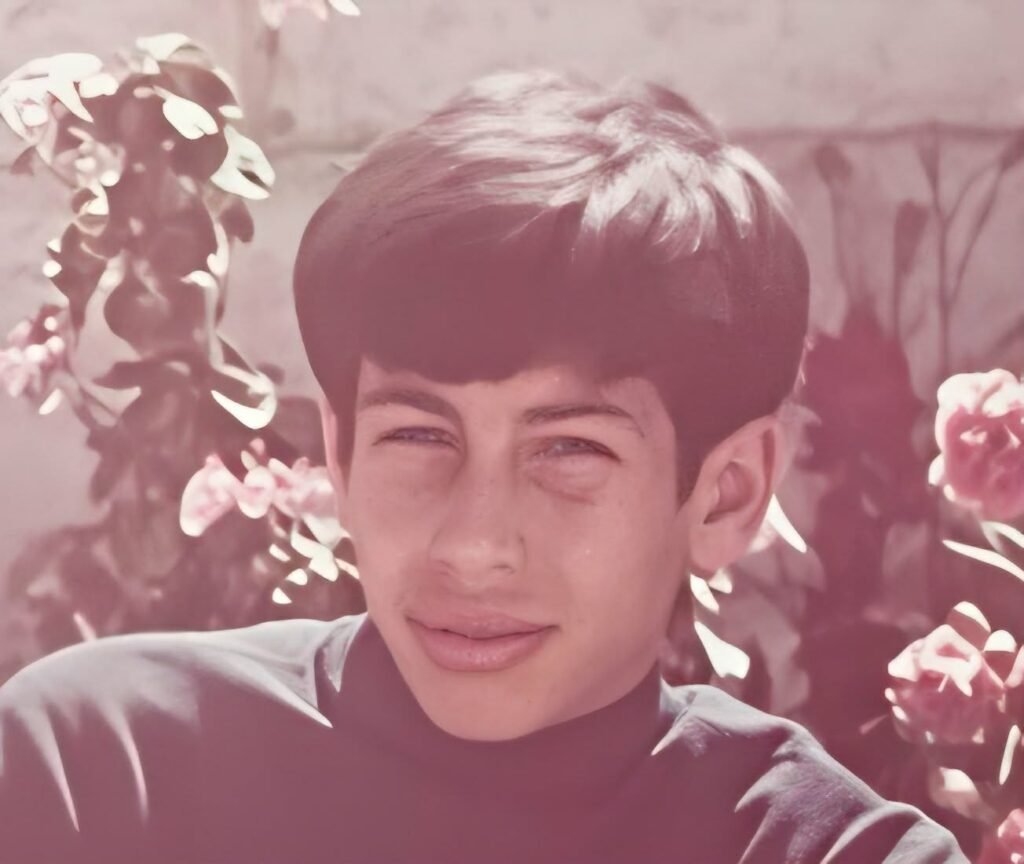 A vintage-style portrait of a young boy with expressive eyes, standing in front of flowers, symbolizing hope and resilience despite a challenging upbringing.