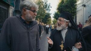 "Director Ismail al-Habbash talking with an Orthodox priest on a street during the filming of Palestinian on the Road."